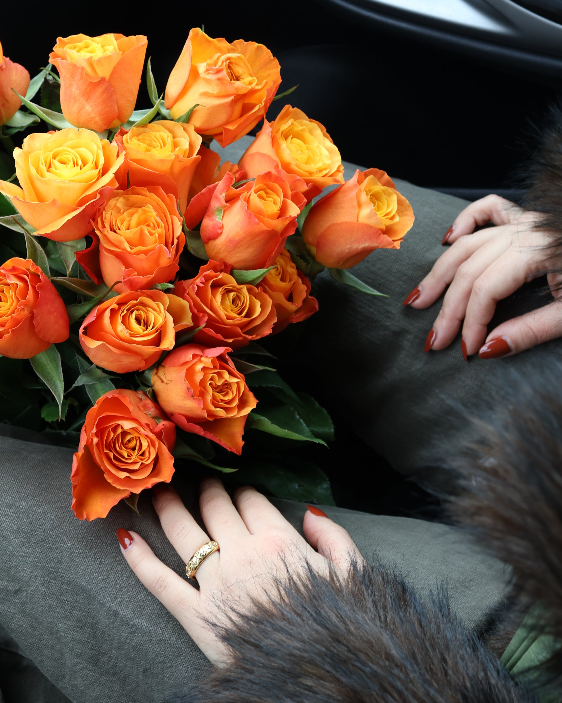 Woman wearing a textured gold astral ring sitting with a large bouquet of orange roses - SOMBRA Jewellery.