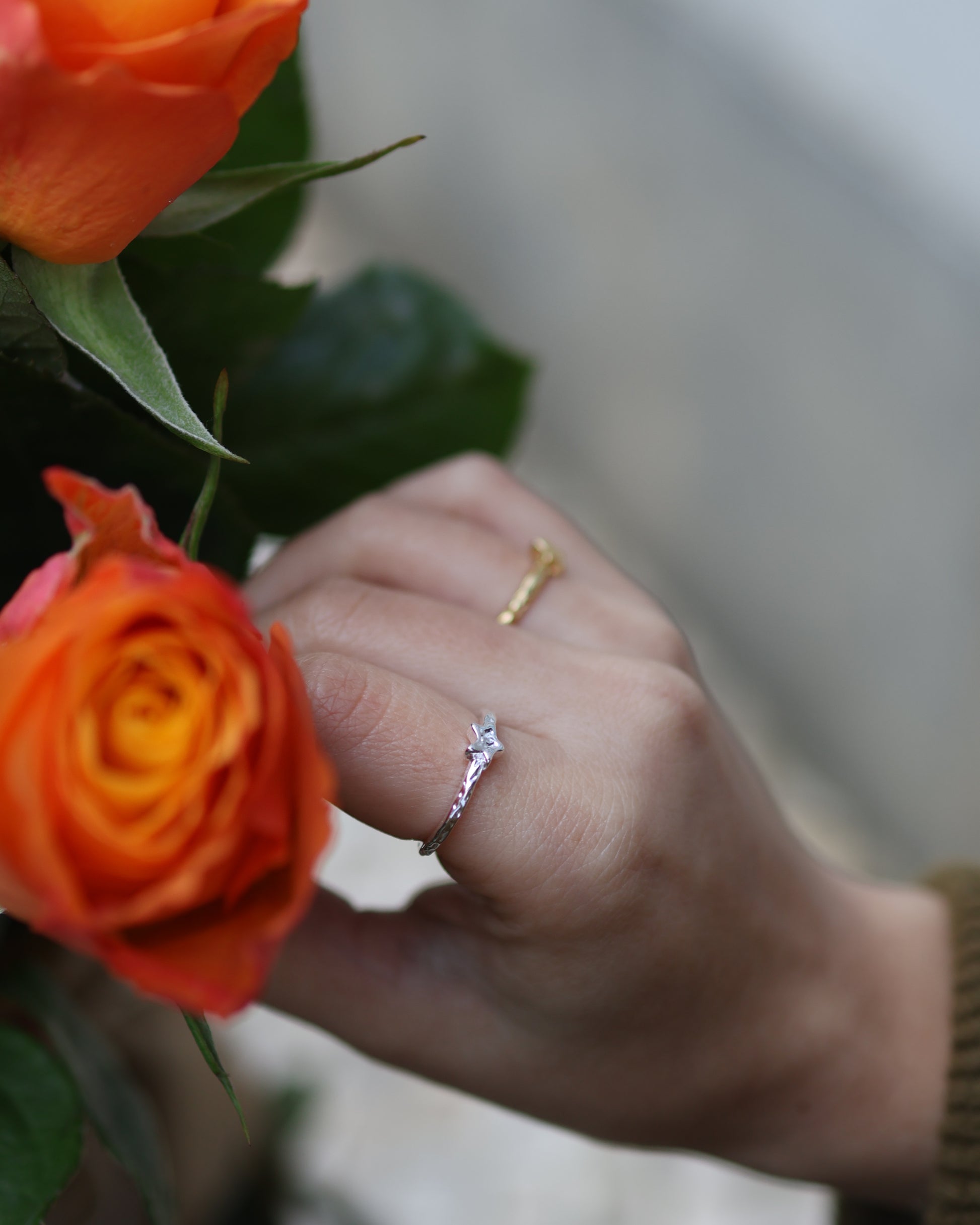Minimalist silver star ring paired with orange roses, perfect for a celestial-themed jewelry gift.