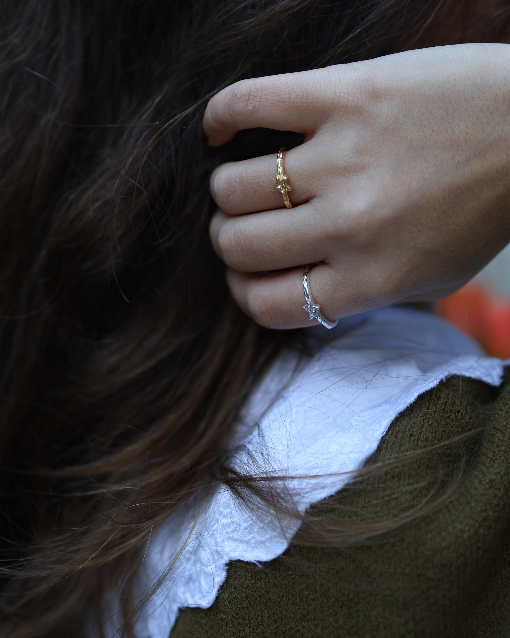 Stacking gold and silver Polaris star rings on a woman's hand for a mixed metal celestial jewelry look.